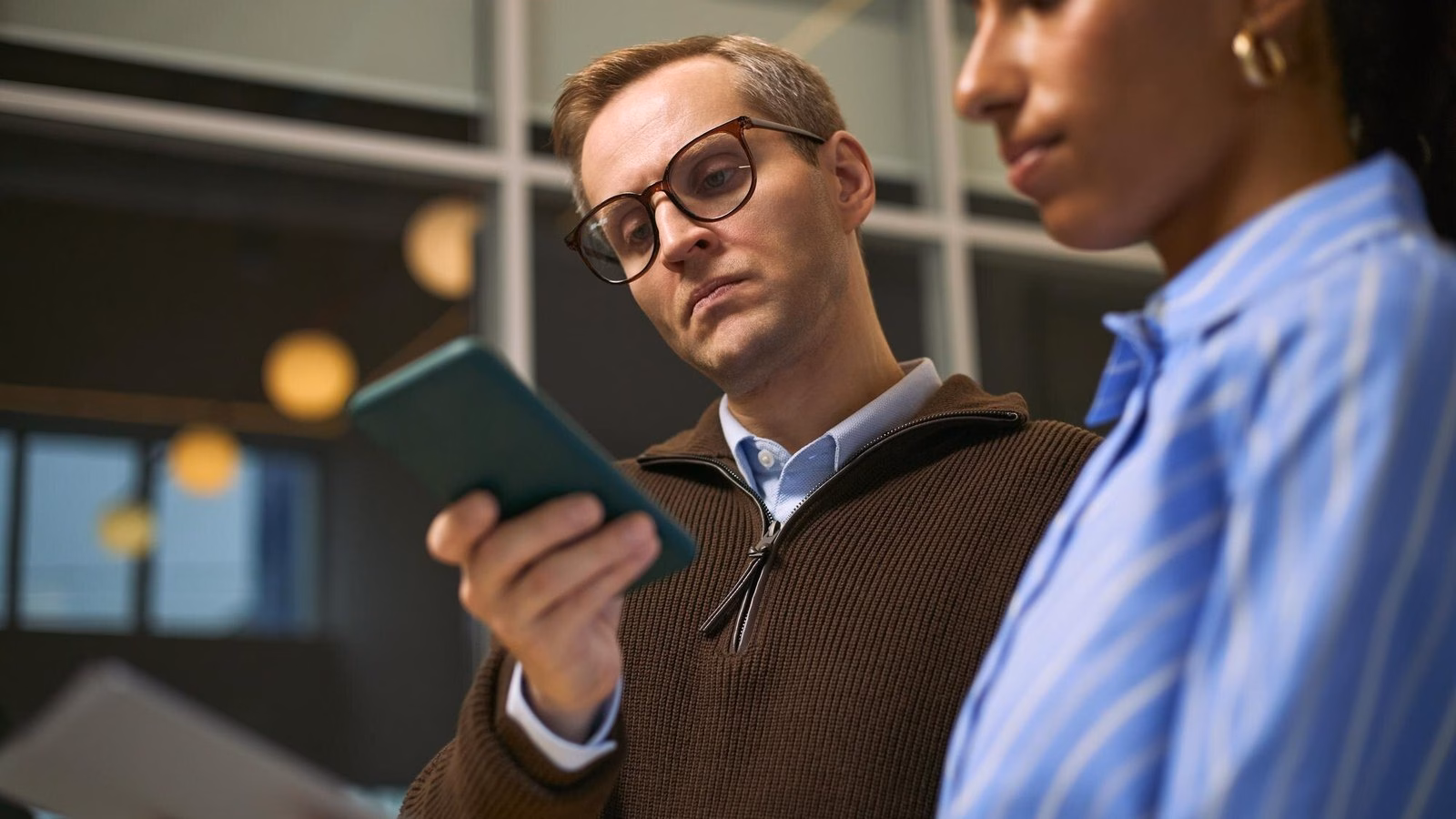 Two colleagues review business information together on a tablet in an office.