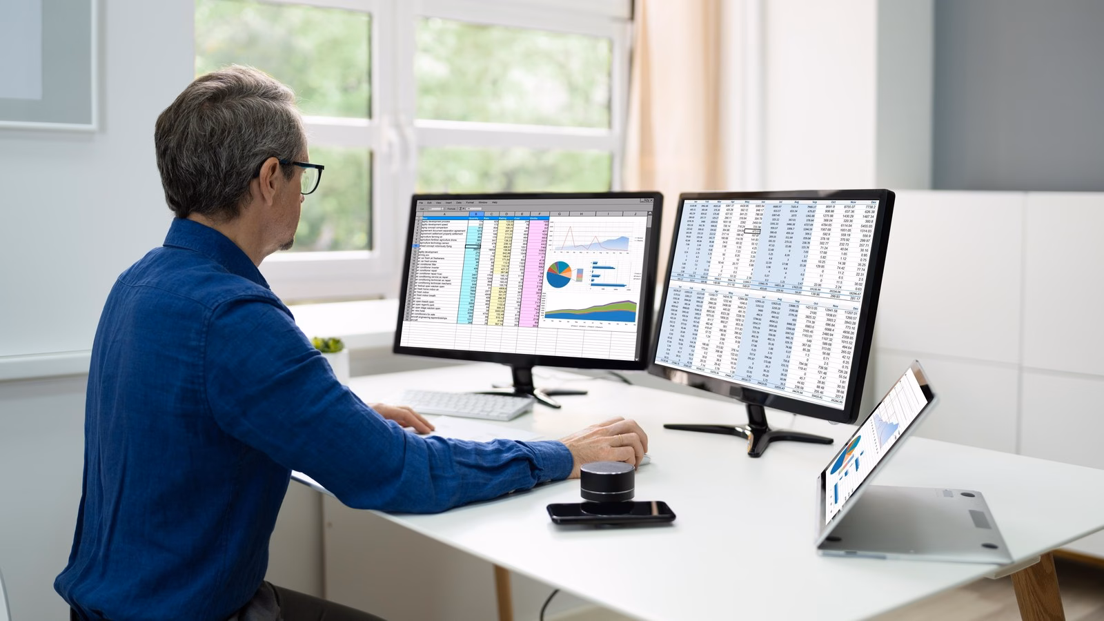 A professional reviewing detailed information across desktop screens.